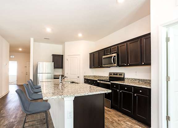 A kitchen with black cabinets and a granite countertop.