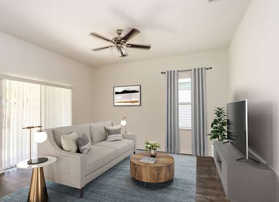 A living room with a beige couch, a coffee table, a television, and a ceiling fan.