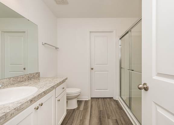 A white bathroom with a sink, toilet and a door.