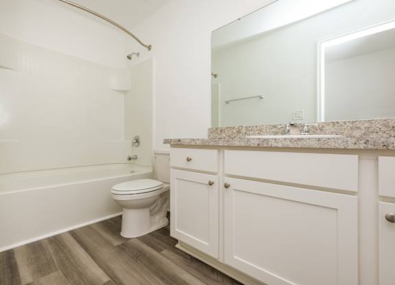 A white toilet sits in a bathroom next to a bathtub.
