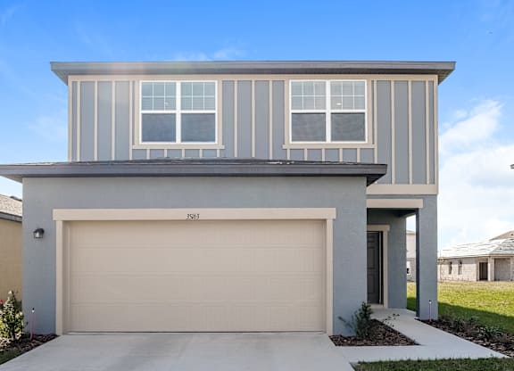 A modern house with a garage door and a driveway.