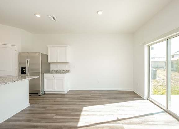 A kitchen with white cabinets and a refrigerator.