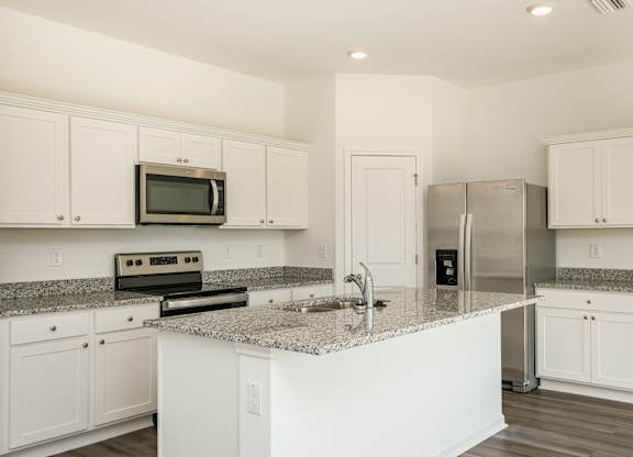 A kitchen with white cabinets and a granite countertop.