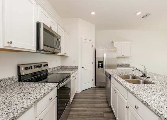 A kitchen with granite countertops and white cabinets.