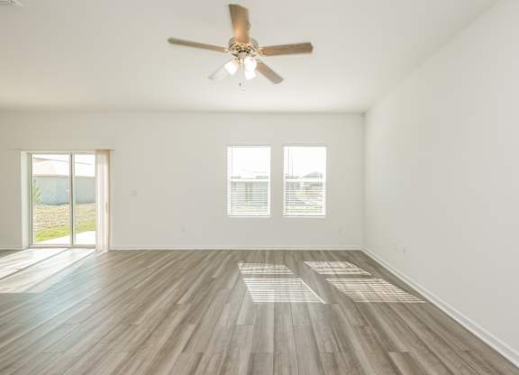 A room with a ceiling fan and wooden flooring.