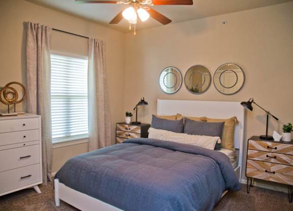 A bedroom with a bed, two nightstands, and a ceiling fan.