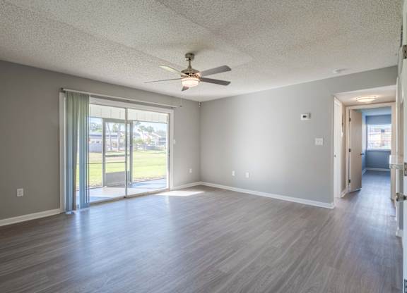 A room with a ceiling fan and sliding glass doors.