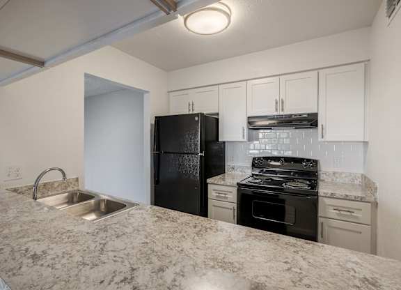 A kitchen with granite countertops and white cabinets.