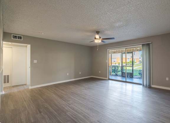 A spacious room with a ceiling fan and sliding glass doors.