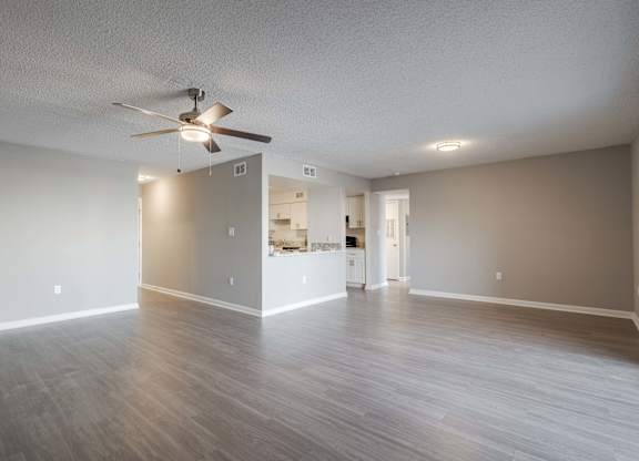 A spacious room with a ceiling fan and lighting fixtures.