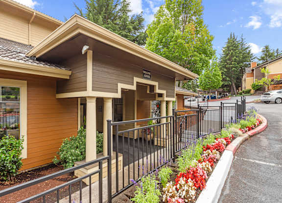 A small building with a brown and tan exterior and a black fence in front at MonteVista Apartments, Oregon