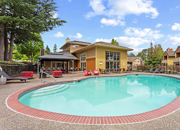 A swimming pool in front of a house with a patio and lounge chairs at MonteVista Apartments, Oregon 97007