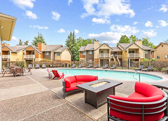 A pool area with red chairs and a hot tub in front of apartment buildings at MonteVista Apartments, Beaverton, OR