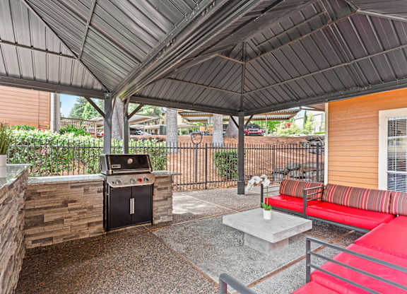 A patio with a grill and a red couch at MonteVista Apartments, Oregon