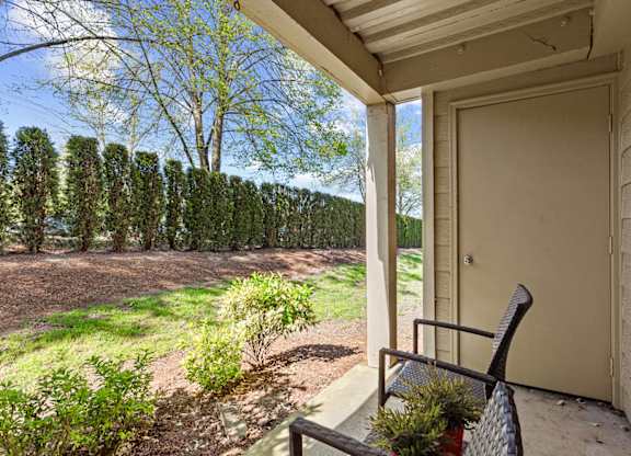 A chair sits on a porch with a view of a tree-lined field at MonteVista Apartments, Beaverton, Oregon