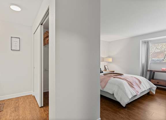 A bedroom with a bed, nightstand, and window at MonteVista Apartments, Beaverton, OR
