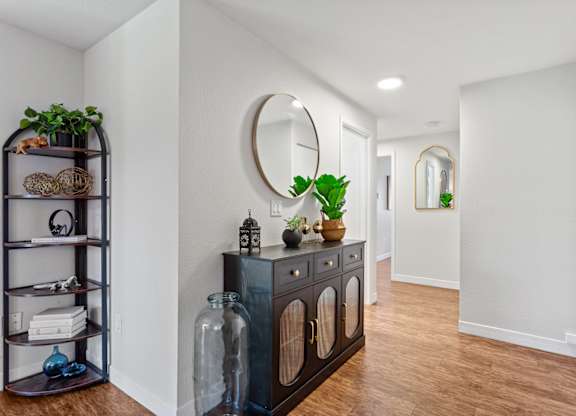 A hallway with a black cabinet and a mirror on the wall at MonteVista Apartments, Beaverton, Oregon