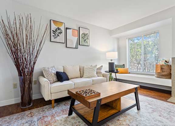 A living room with a white couch, a wooden coffee table, and a vase with brown branches at MonteVista Apartments, Oregon 97007