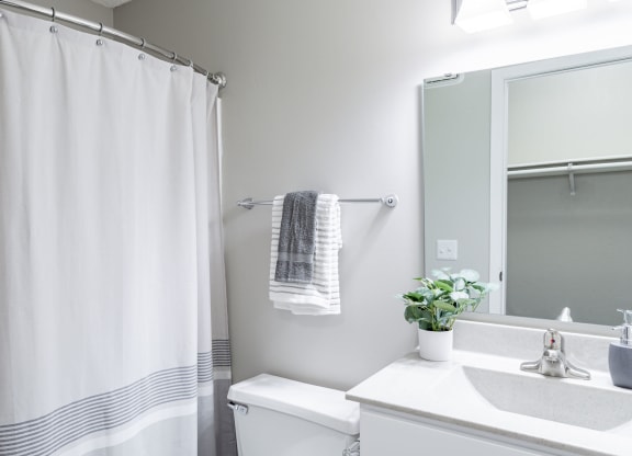 a bathroom with a white sink and toilet and a white shower curtain