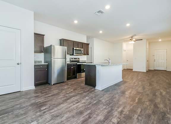 A kitchen with a refrigerator, microwave, and oven.