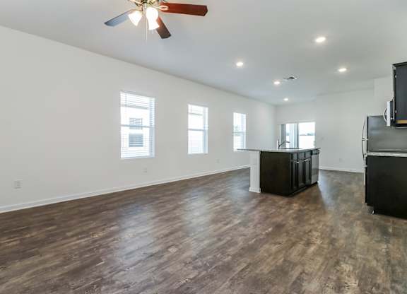 A room with a ceiling fan and wooden flooring.