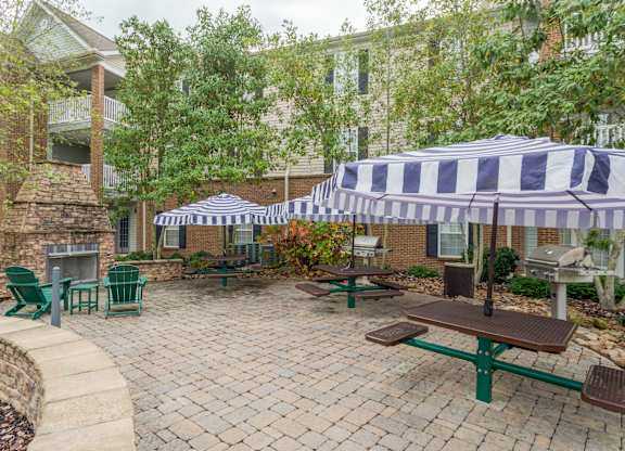 Apartments in Sevierville for Rent – Overlook at Allensville -   A patio with a table and chairs under a striped umbrella.