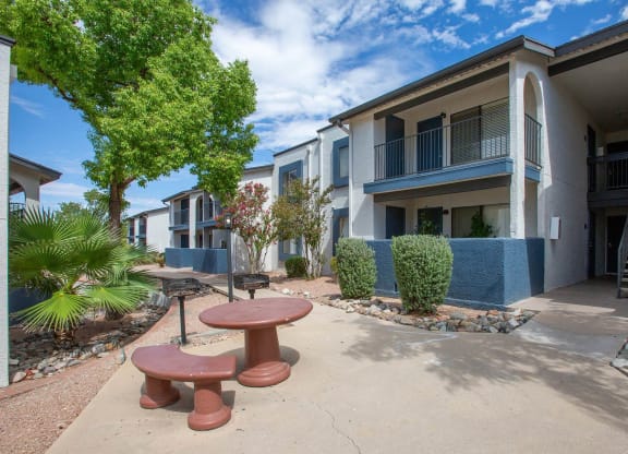a courtyard with a picnic table and benches in front of an apartment building