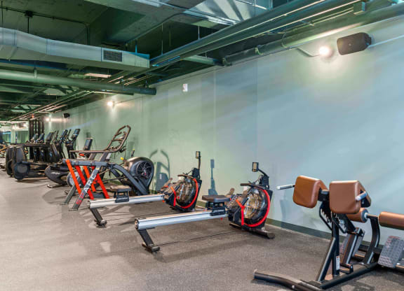 a gym with bikes and weights in a room with a white wall