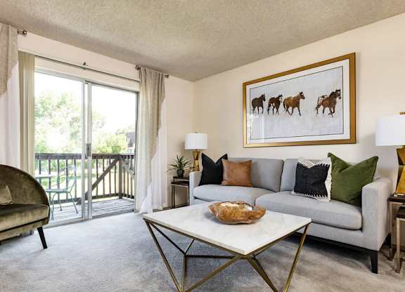 Living room with sliding glass doors leading to private balcony at Willowstone Apartments in Denver CO 80231