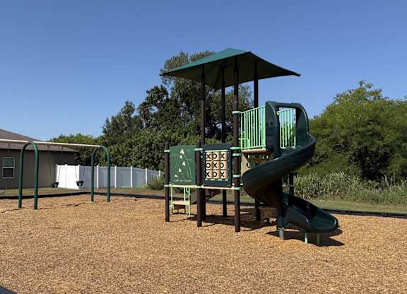 A playground with a green slide and a sign with letters and numbers.