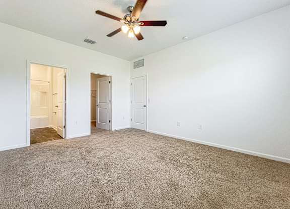 A room with a ceiling fan and carpeted floor.
