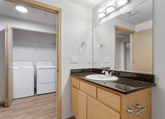 A bathroom with a sink, mirror, and two washing machines.