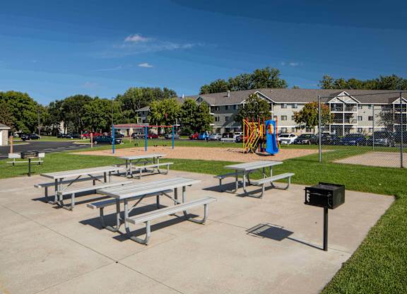 A playground with a slide and picnic tables.