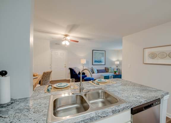 A kitchen with a marble countertop and a stainless steel sink.