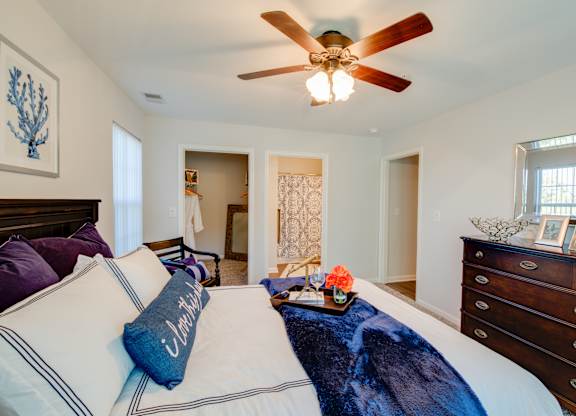 A bedroom with a bed, dresser, and ceiling fan.