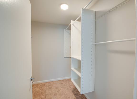 A white closet with shelves and a light on the ceiling.