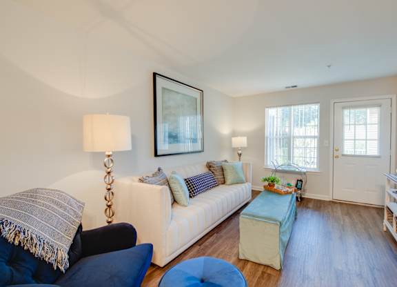 A living room with a white couch and a blue ottoman.