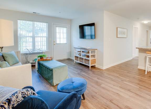 A living room with a blue ottoman and a white couch.