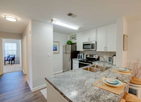 A kitchen with granite countertops and white cabinets.