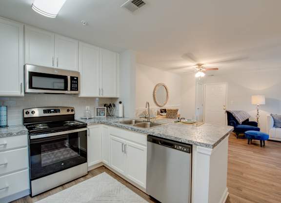 A modern kitchen with white cabinets and stainless steel appliances.