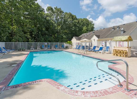 A large outdoor swimming pool surrounded by trees and a fence.