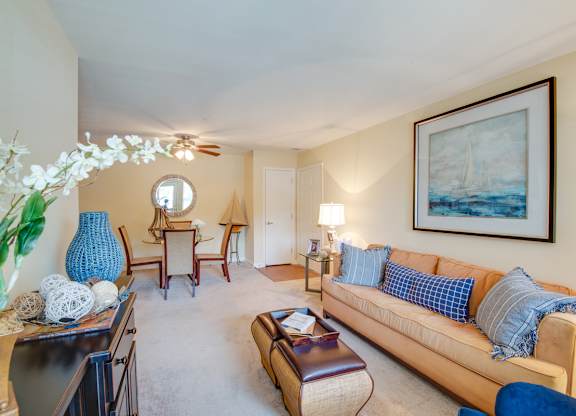 A living room with a blue couch and a painting on the wall.