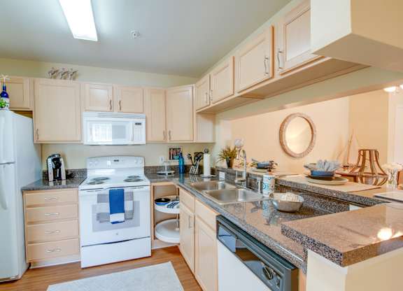 A kitchen with a white refrigerator, white oven, and wooden cabinets.
