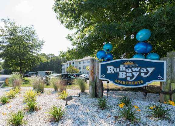 A sign that says Runaway Bay is in front of a street.