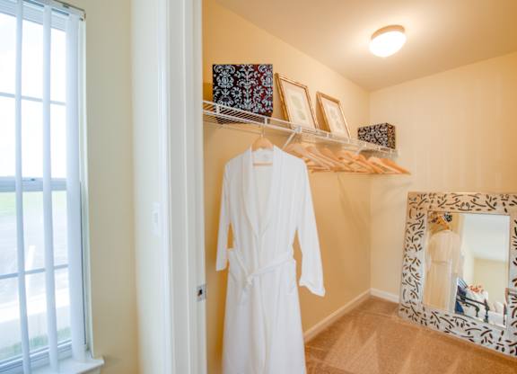 A white robe hanging on a rack in a room.