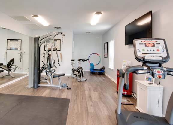 A gym with a variety of exercise equipment including treadmills, stationary bikes, and weight machines.