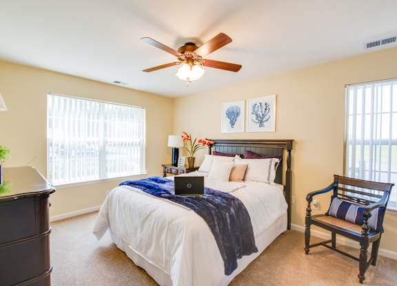 A bedroom with a bed, a chair, and a ceiling fan.