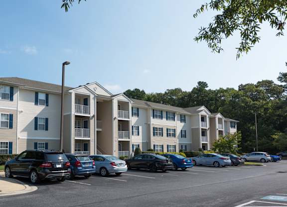 A parking lot with cars and apartment buildings in the background.