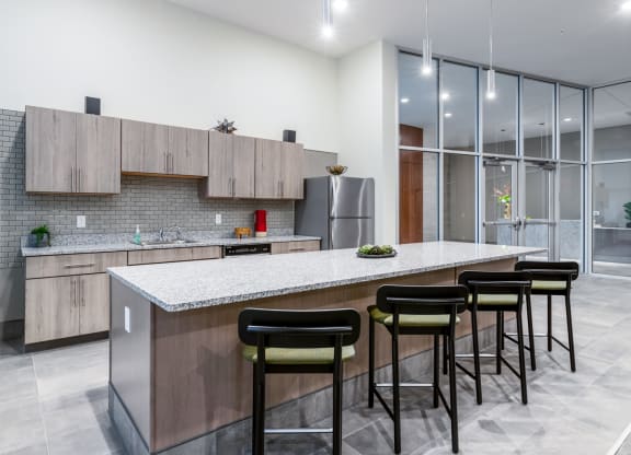 a kitchen with a large island with bar stools and a stainless steel refrigerator