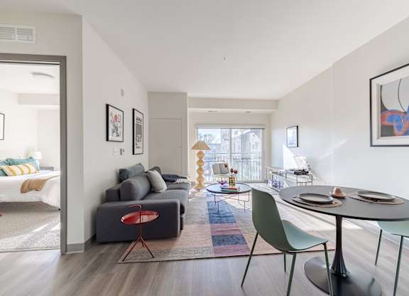 A modern living room with a grey couch, a red chair, a green chair, and a round table.